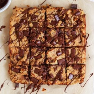 chocolate chip blondies drizzled in chocolate on parchment paper