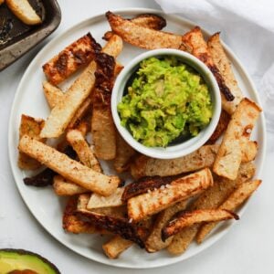 baked jicama fries on plate with mashed avocado