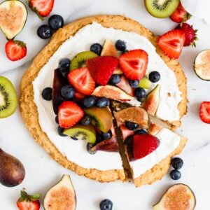 full vegan fruit pizza with slice out of it