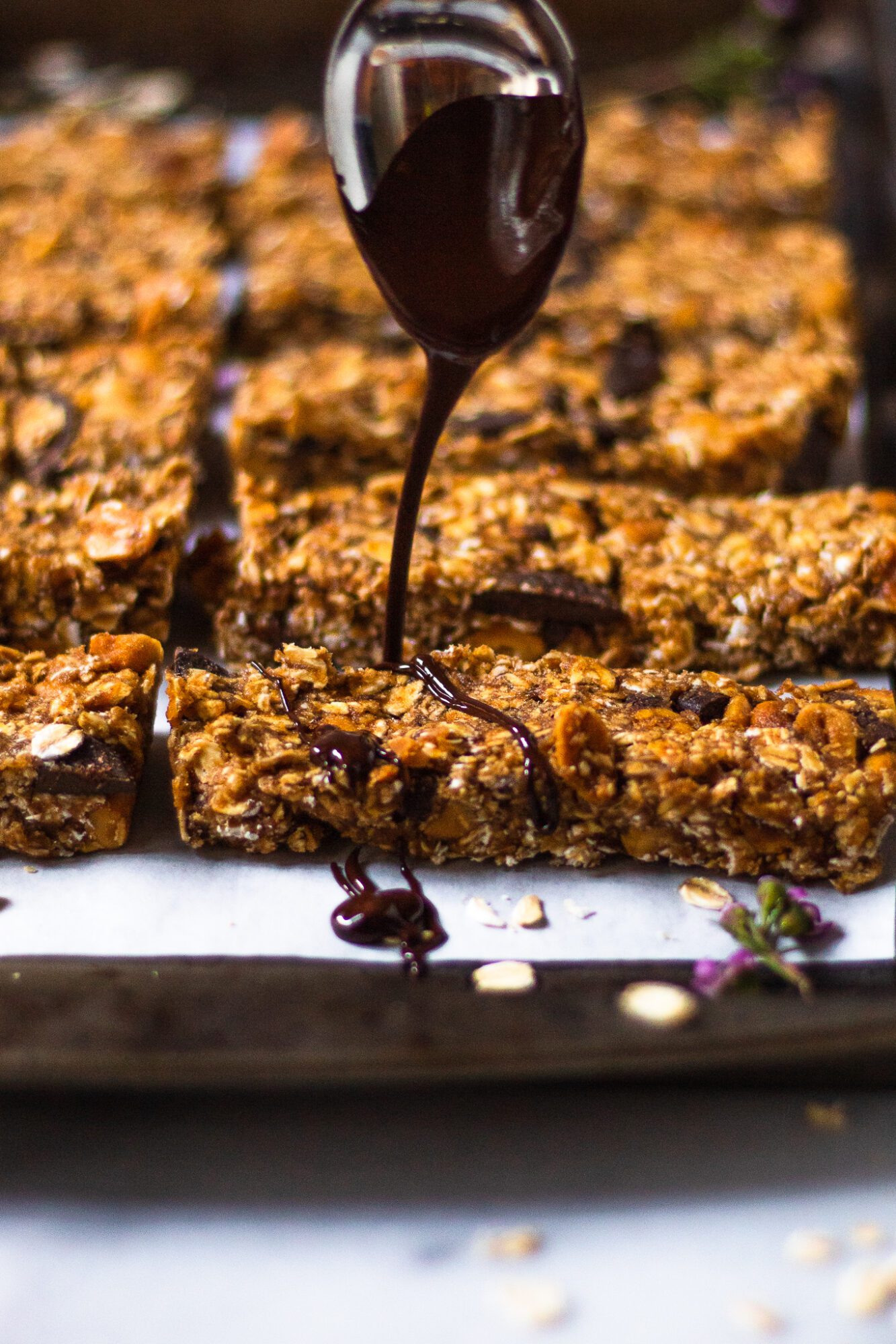 spoon drizzling chocolate over no bake granola bars