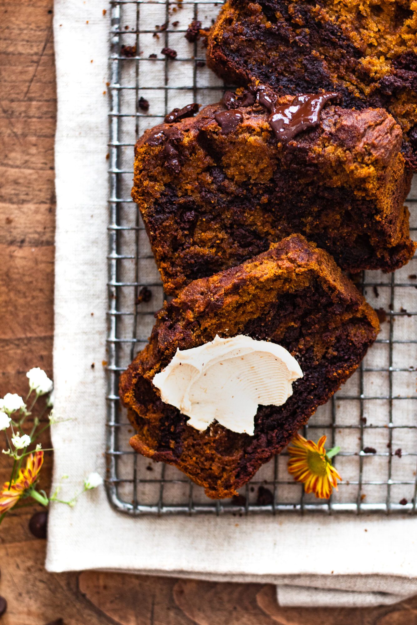 slices of pumpkin bread on cooling rack with vegan cream cheese