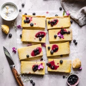 sliced Paleo vegan lemon bars with blueberry jam on top with a knife next to it