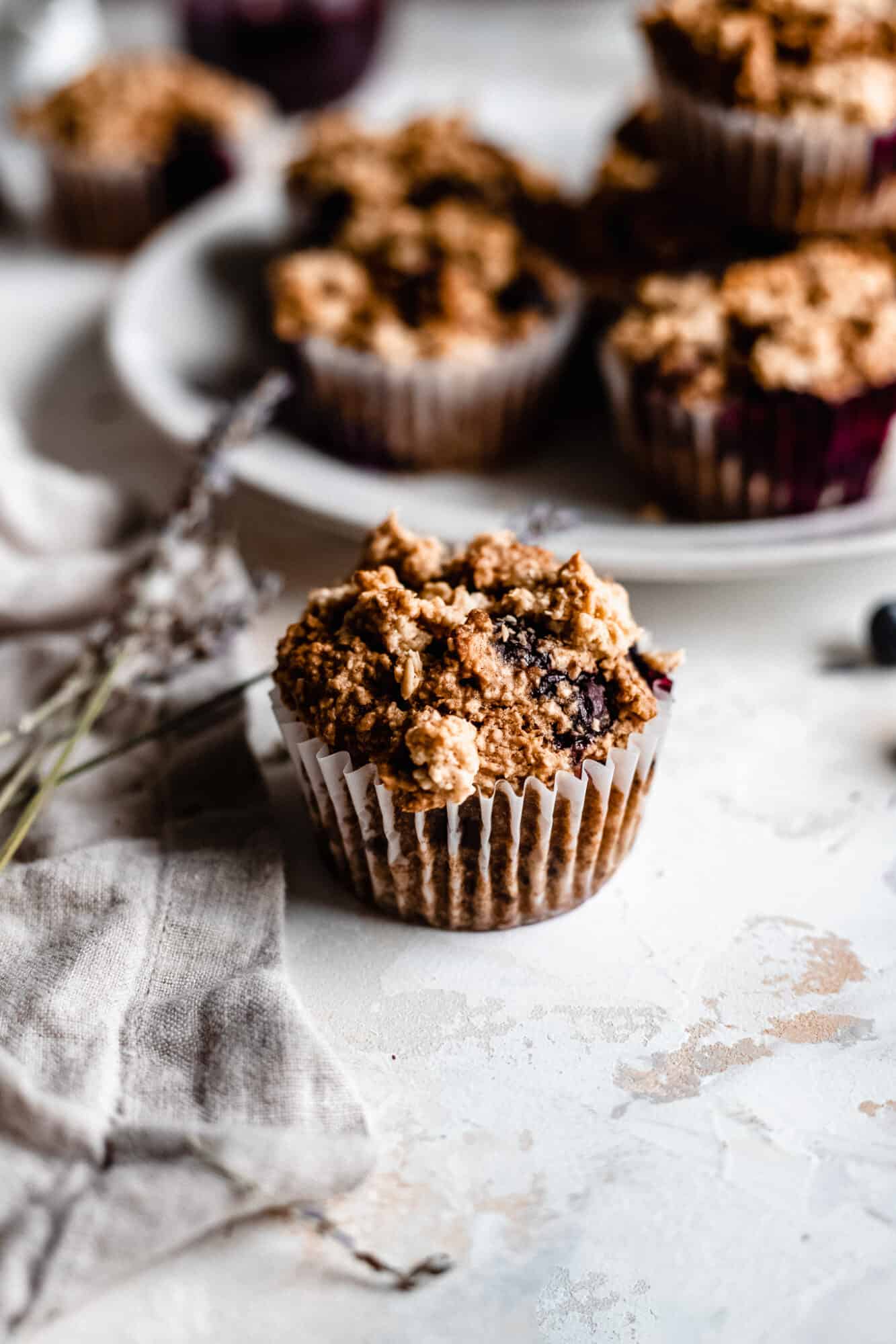 oatmeal blueberry muffin next to plate of muffins
