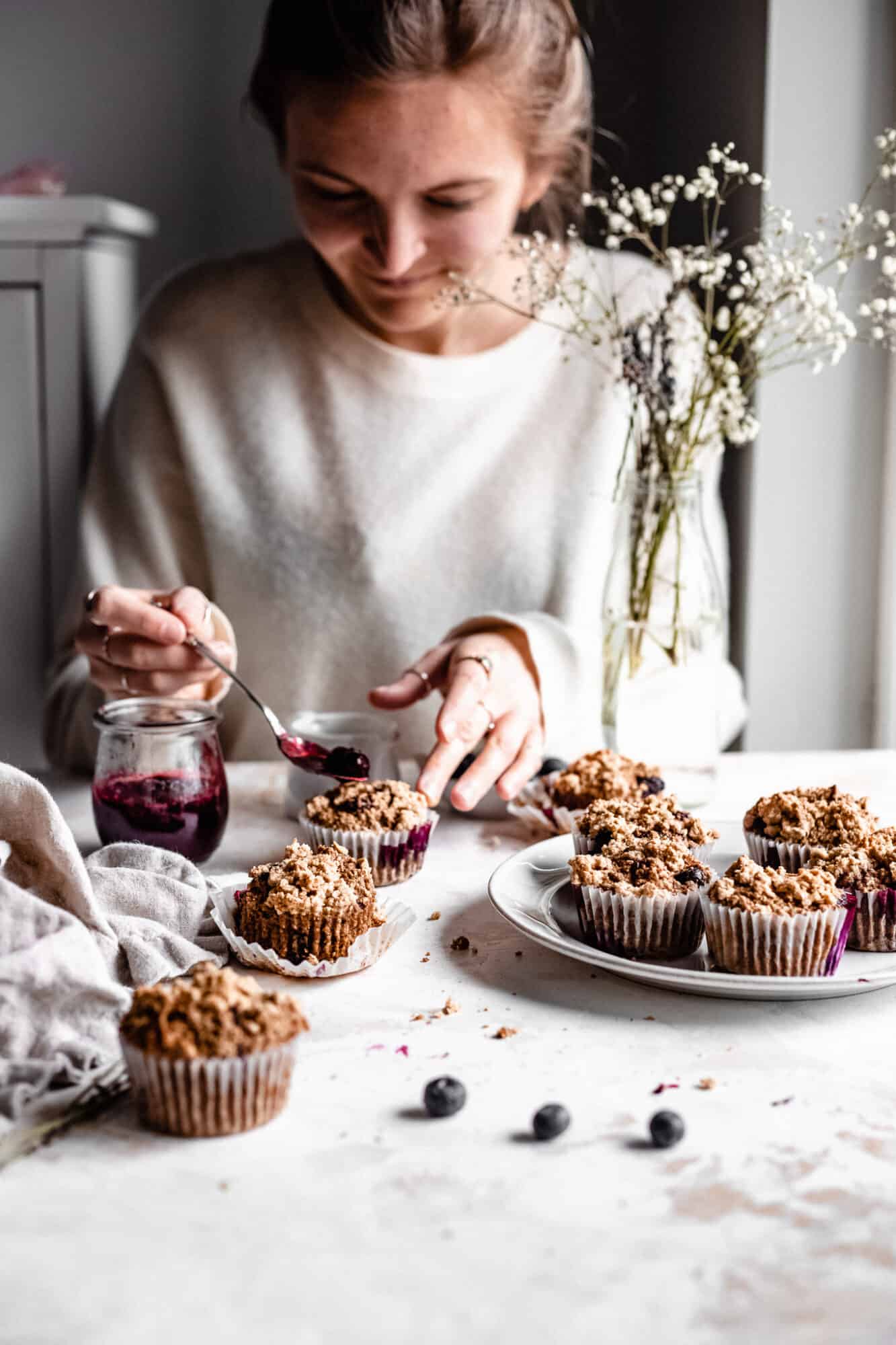 placing jam on blueberry muffin