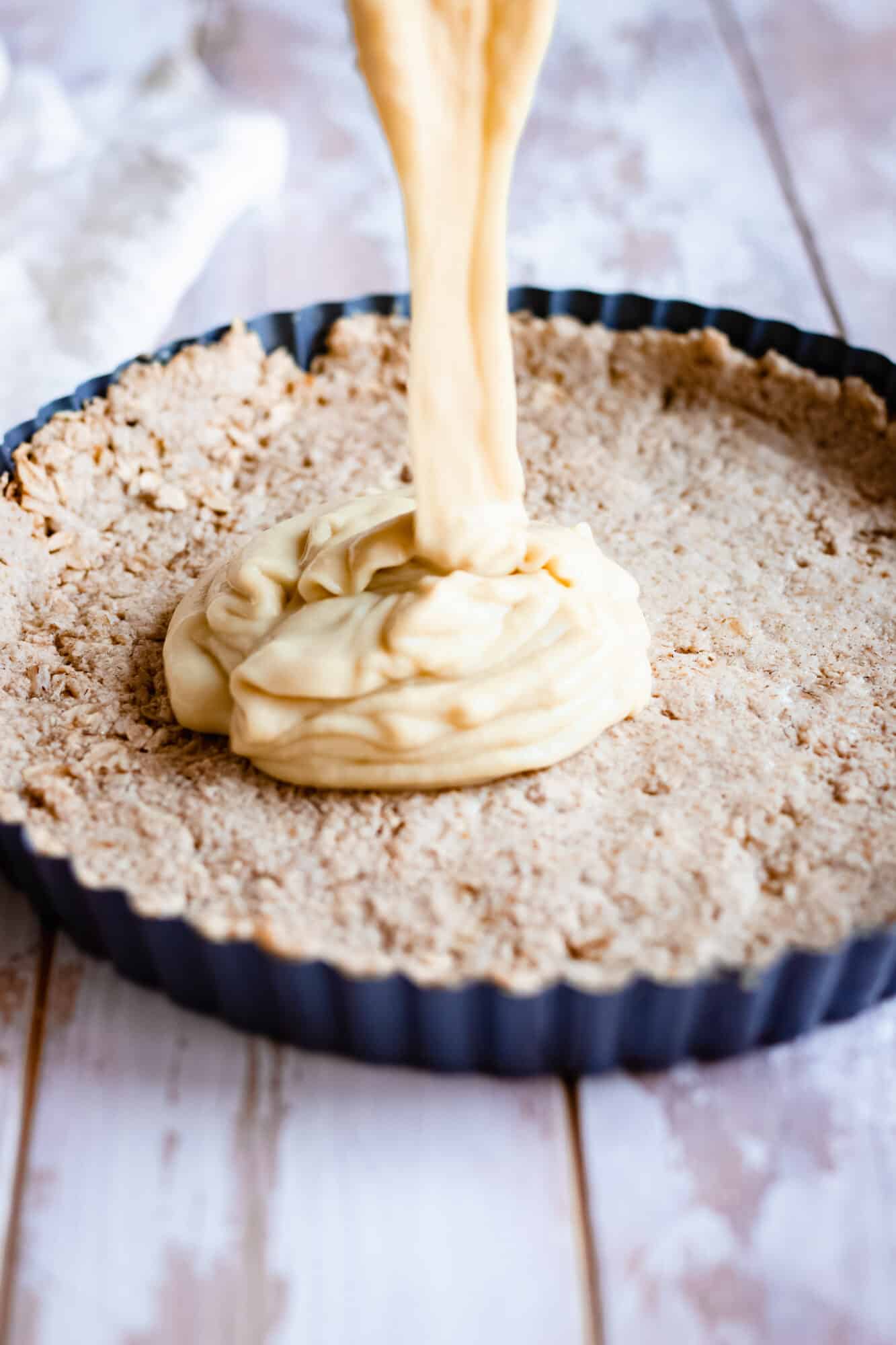 pouring the lemon custard filling into the gluten free oat crust