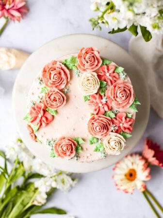 buttercream flower cake with flowers around it on marble