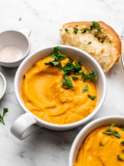 bowls of vegan butternut squash and sweet potato soup with parsley on it