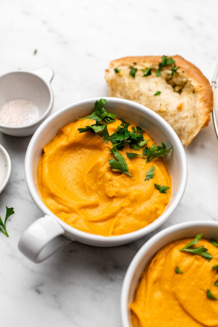 bowls of vegan butternut squash and sweet potato soup with parsley on it