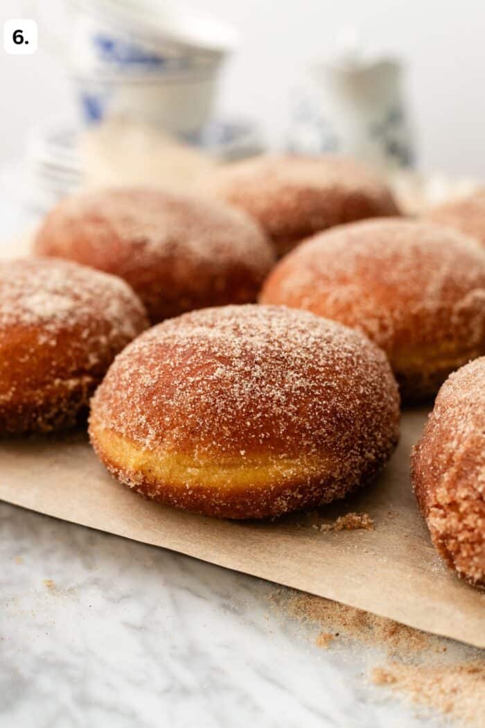 coated cinnamon sugar pumpkin doughnuts on a cooling rack before filling.