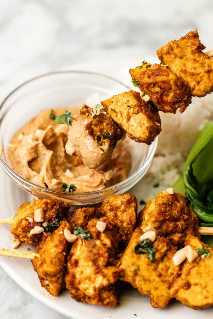 dipping the tofu satay into peanut sauce