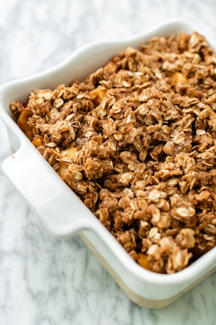 Assemble the apple crisp and bake! Then top the apple layer with the cinnamon oat crumble. Place into the oven, covered with some tin foil for the start, to bake.