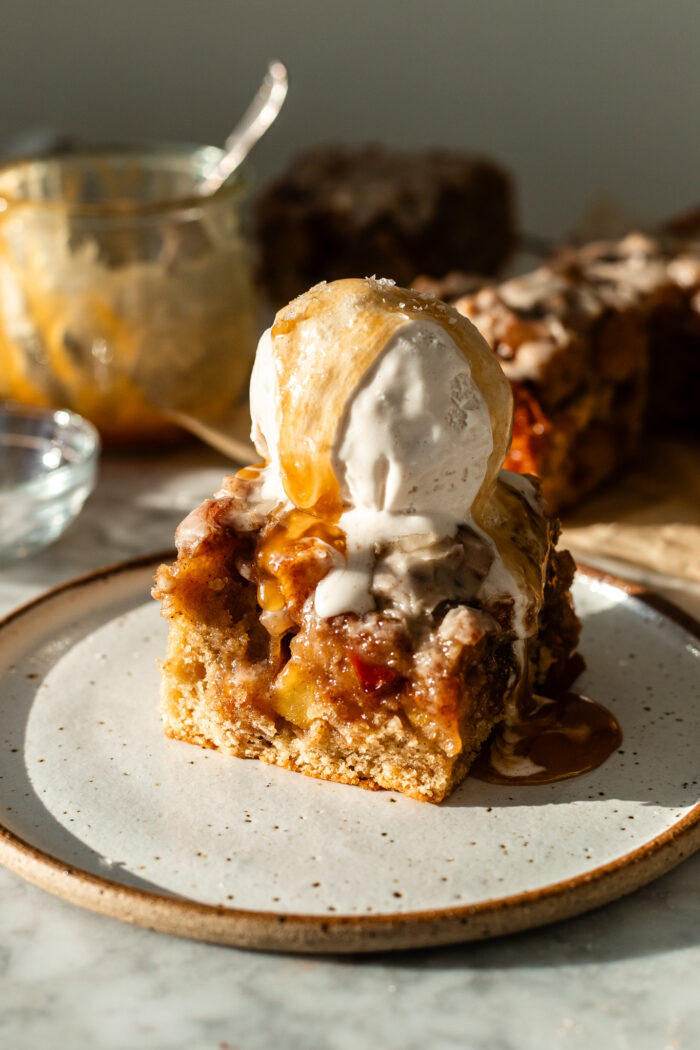 serving the vegan apple fritter cake with ice cream and caramel sauce on top