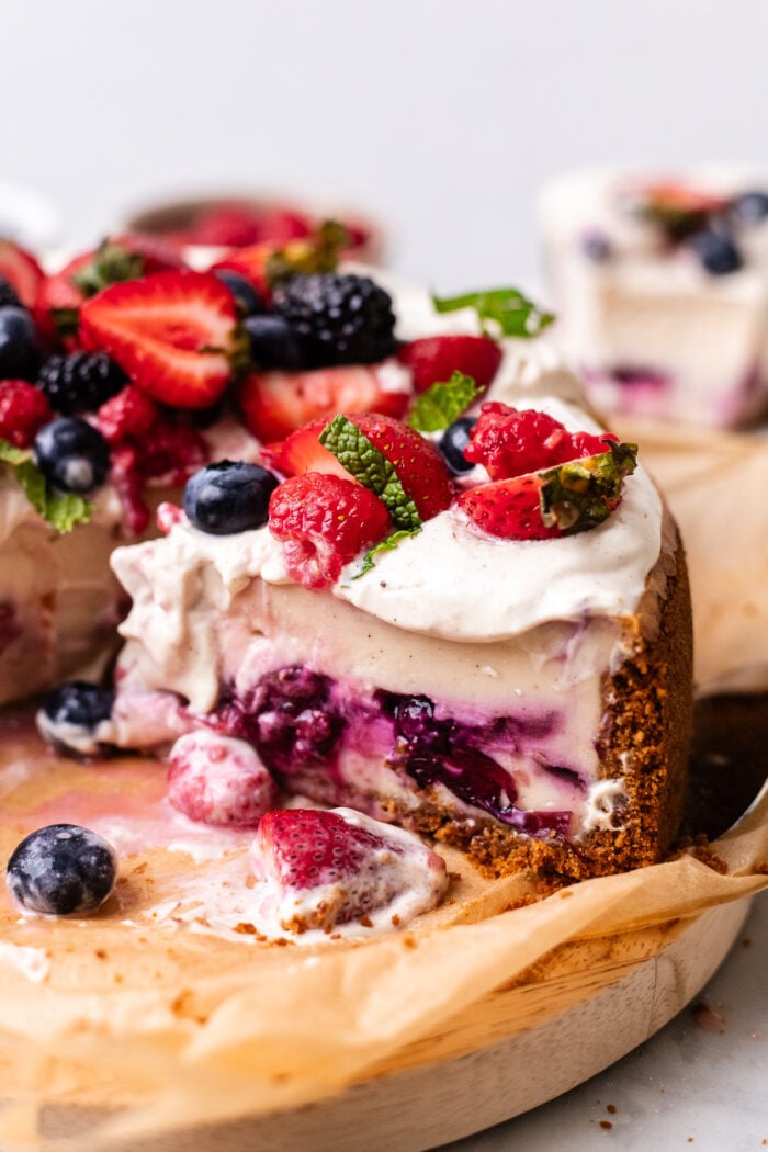 sliced vegan berry chantilly cheesecake on wooden board