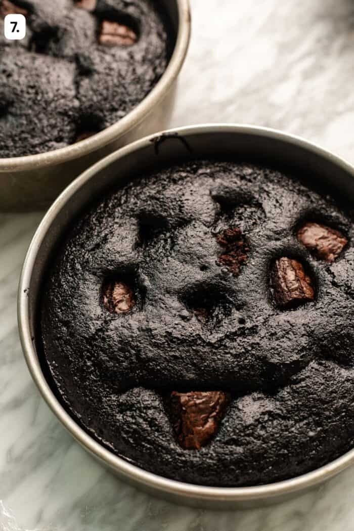 baked brownie cake layers with brownie bites puffing out of the cake batter.
