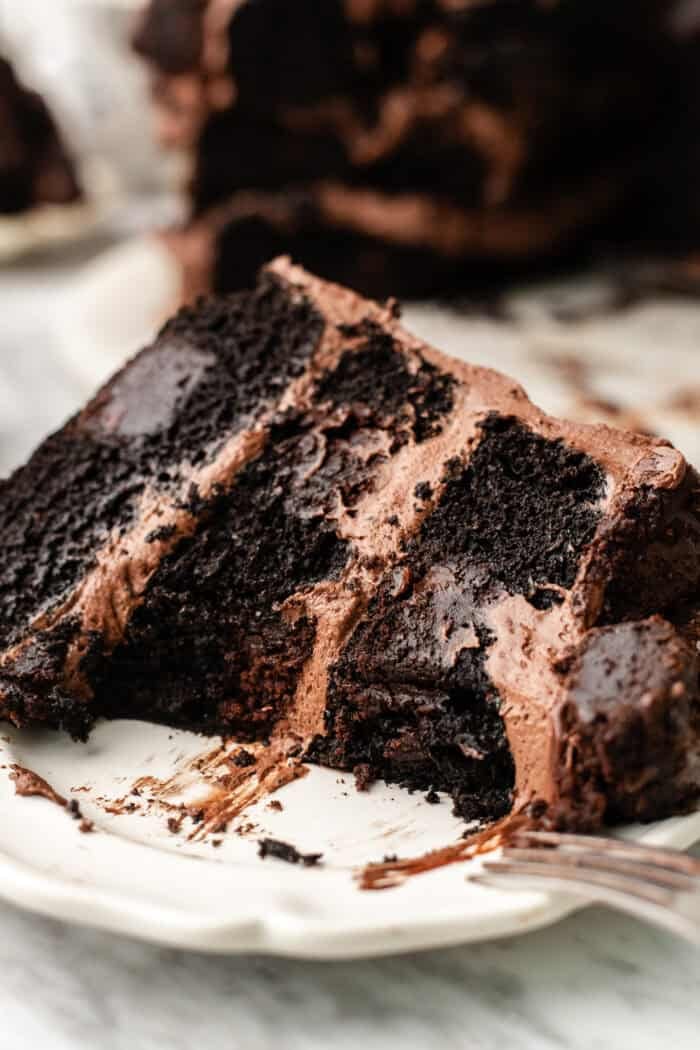 slice of vegan brownie cake on a plate with a fork taking a bite out of it.