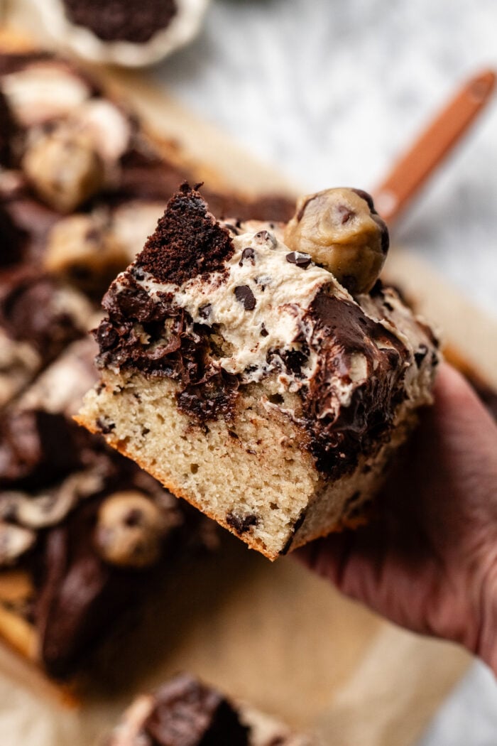 hand holding slice of brownie cookie dough cake