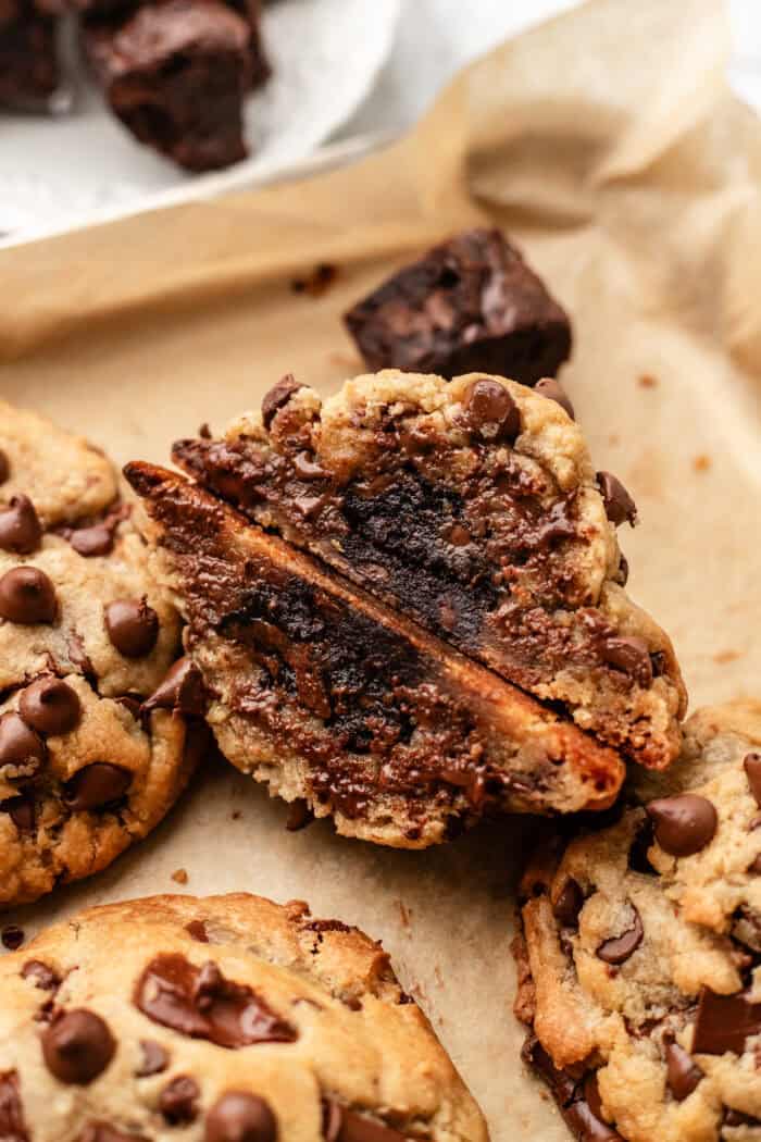 sliced open vegan brownie cookie leaning on top of another cookie on a baking sheet.