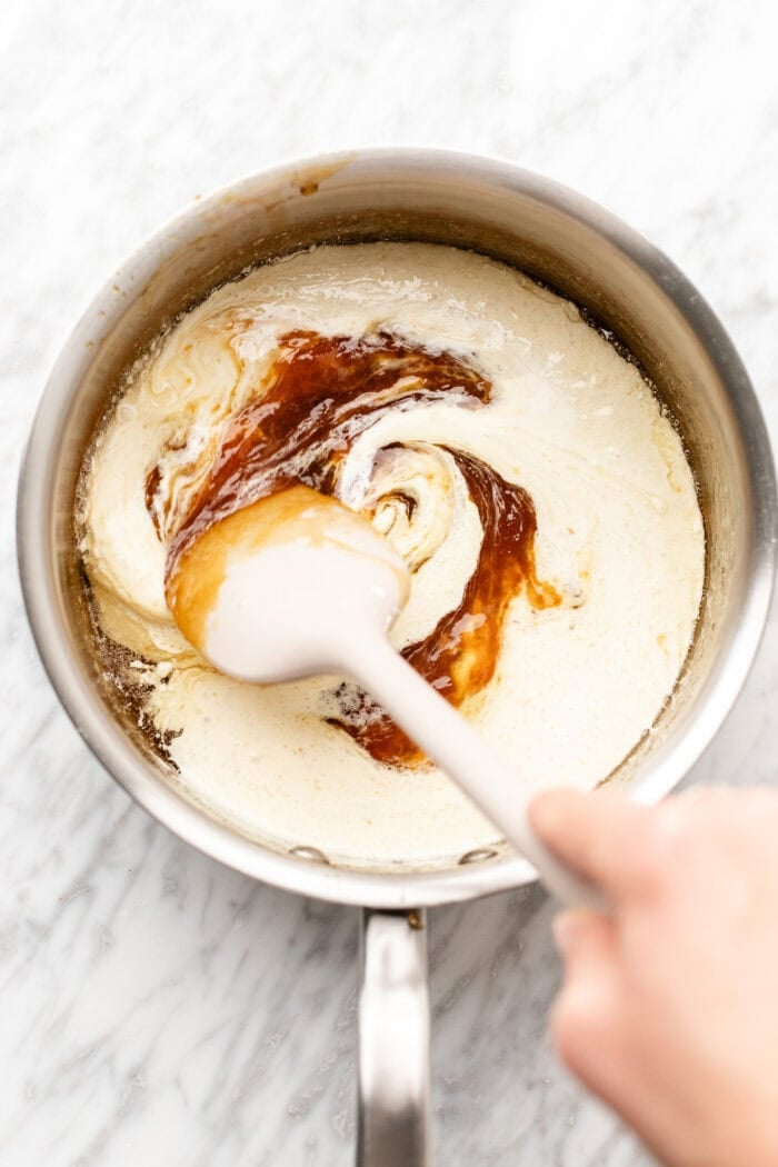 stirring in the vegan heavy cream to integrate into the caramel