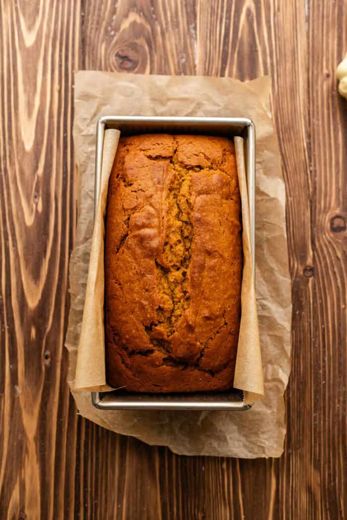 pumpkin bread after baking in a loaf tin on a wooden table.