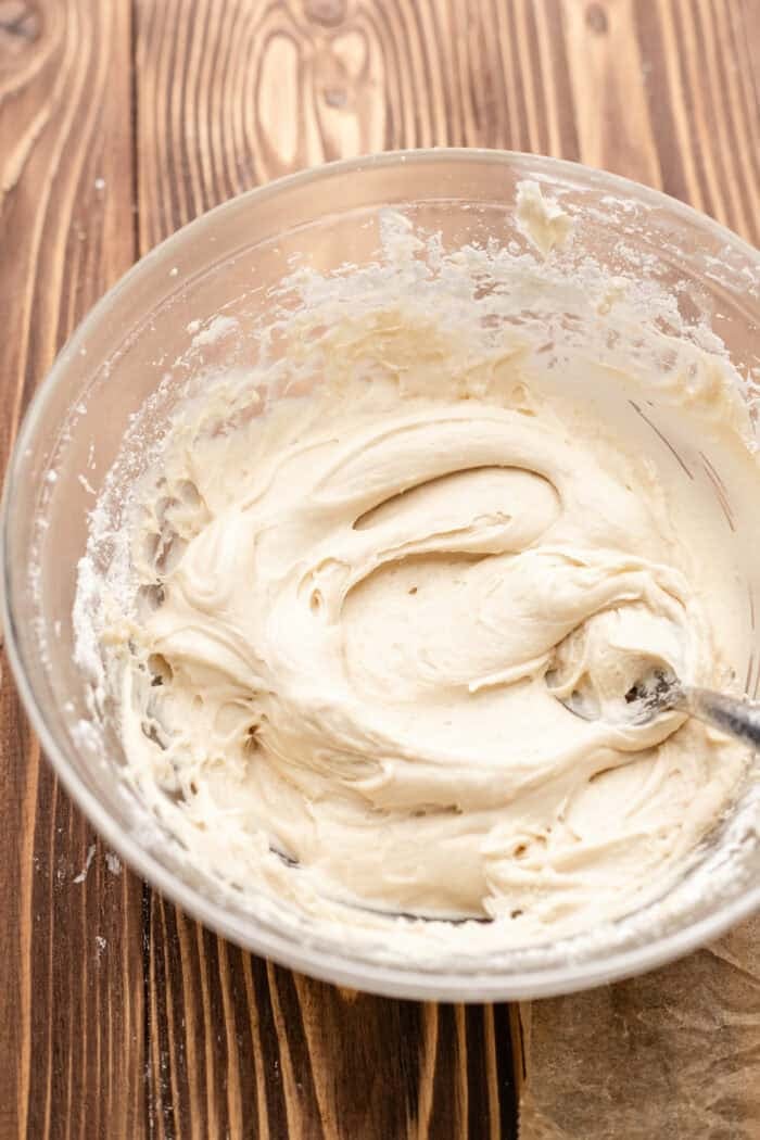 maple cream cheese frosting in a bowl on a wooden table.