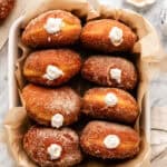 vegan pumpkin spice doughnuts in a container on a marble table.