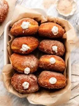 vegan pumpkin spice doughnuts in a container on a marble table.